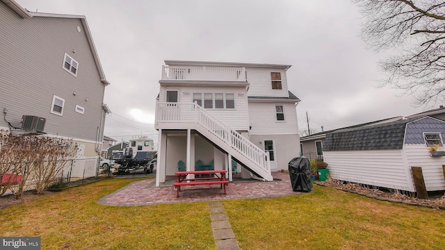 back of house with central air condition unit, a lawn, and a patio