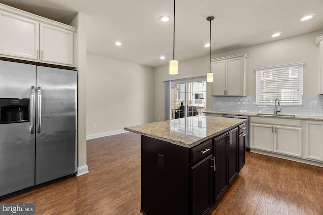 kitchen featuring stainless steel appliances, sink, white cabinets, a kitchen island, and hanging light fixtures