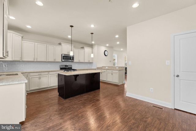 kitchen with white cabinetry, stainless steel appliances, and hanging light fixtures