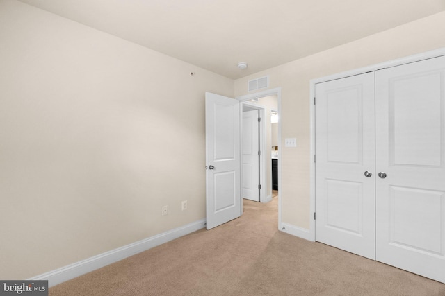 unfurnished bedroom with light carpet and a closet