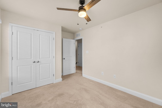 unfurnished bedroom with ceiling fan, light carpet, and a closet