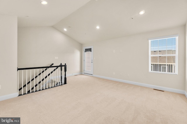 empty room with light colored carpet and vaulted ceiling