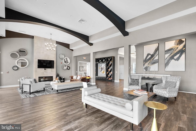 living room with beamed ceiling, dark hardwood / wood-style flooring, a chandelier, and a fireplace