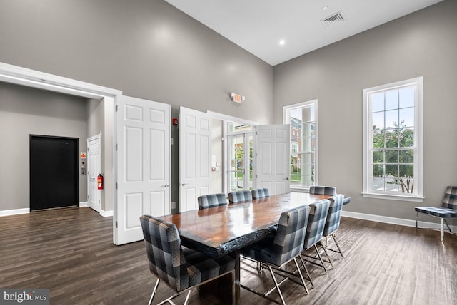 dining space with dark hardwood / wood-style flooring and a high ceiling