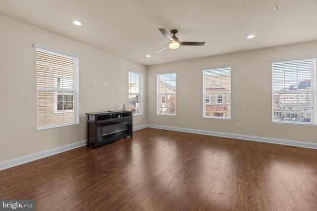 living room featuring a wealth of natural light, ceiling fan, and dark wood-type flooring