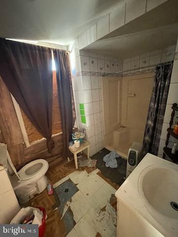 bathroom featuring tile patterned floors, walk in shower, sink, tile walls, and toilet