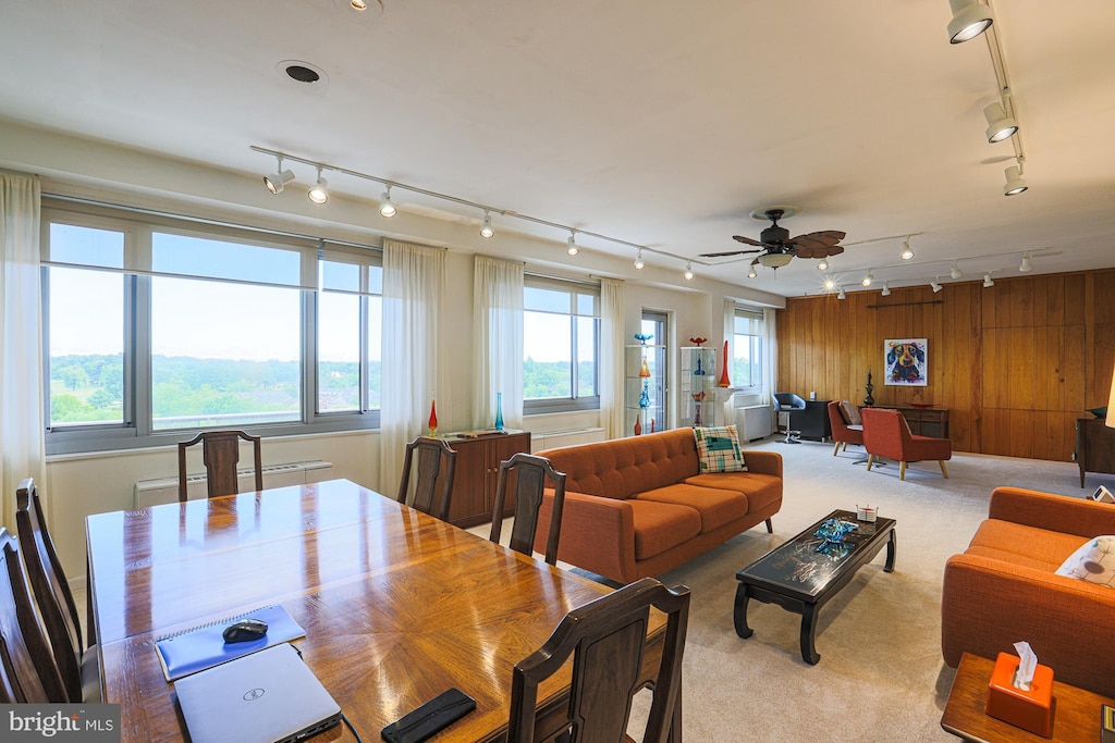 carpeted dining room featuring plenty of natural light, wooden walls, and ceiling fan