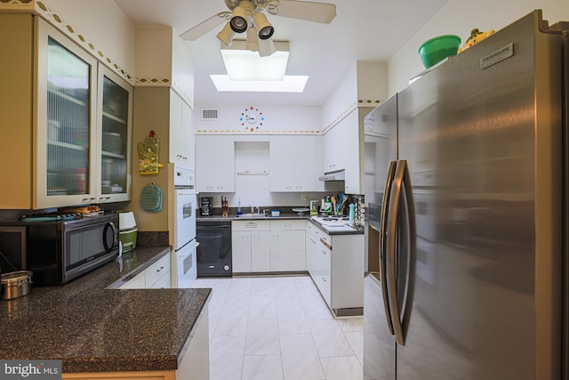 kitchen with a skylight, white cabinetry, white double oven, black dishwasher, and stainless steel fridge