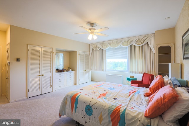 carpeted bedroom with ceiling fan and multiple closets