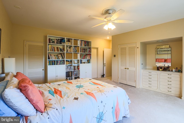 bedroom with light carpet, two closets, and ceiling fan