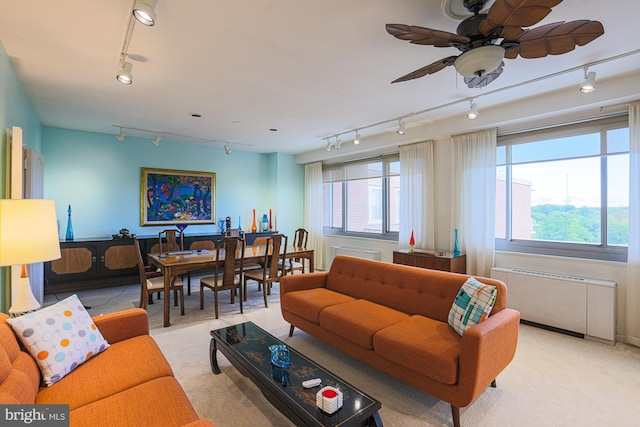 carpeted living room featuring ceiling fan, radiator heating unit, and track lighting