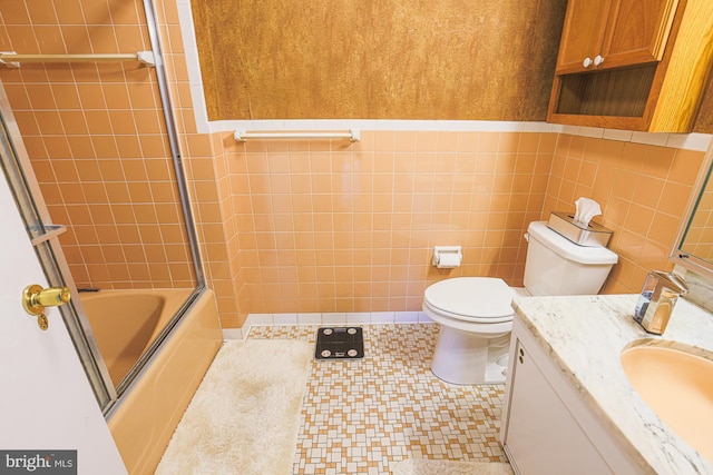 full bathroom featuring toilet, vanity, tile walls, and combined bath / shower with glass door