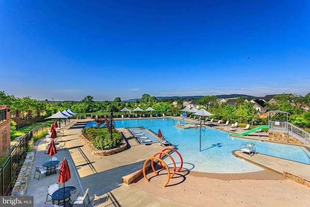 view of swimming pool with a patio and a water slide