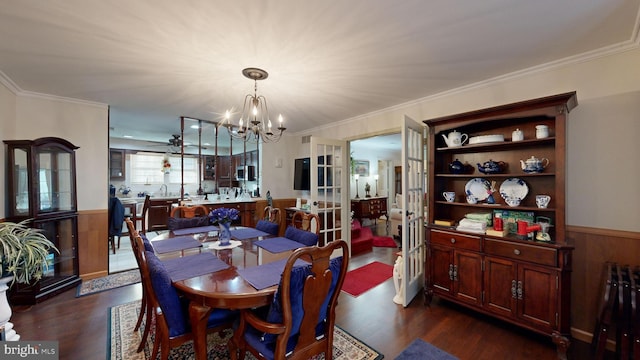 dining room featuring wood walls, crown molding, dark wood-type flooring, and a chandelier