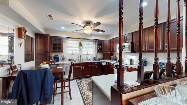 kitchen with appliances with stainless steel finishes, backsplash, sink, a breakfast bar area, and light tile patterned flooring