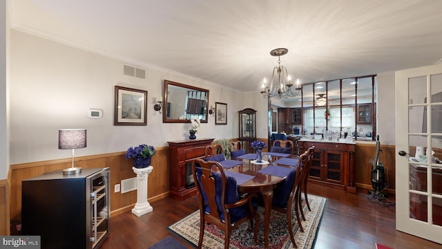 dining area with a chandelier, ornamental molding, wooden walls, and dark wood-type flooring