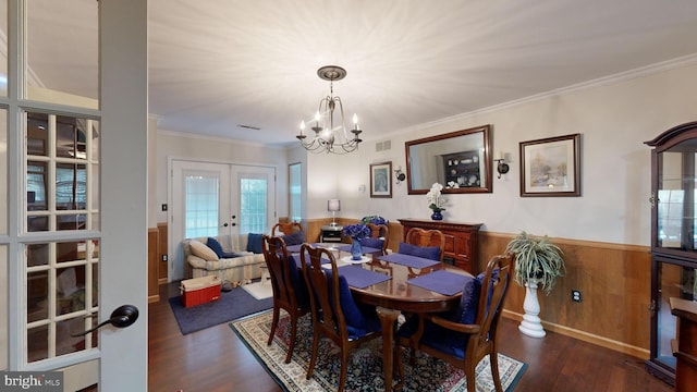 dining space with dark hardwood / wood-style flooring, crown molding, french doors, and a chandelier