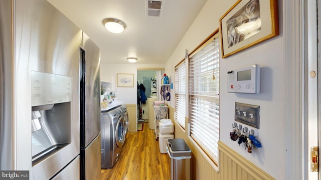 kitchen with light wood-type flooring, stainless steel refrigerator, and washing machine and dryer