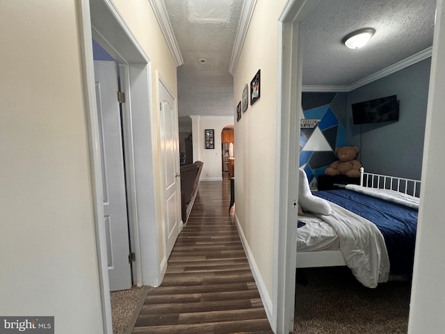 corridor with a textured ceiling, dark hardwood / wood-style flooring, and ornamental molding