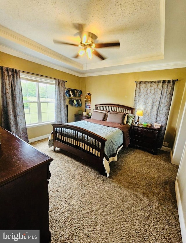 carpeted bedroom featuring ceiling fan, crown molding, a textured ceiling, and a tray ceiling