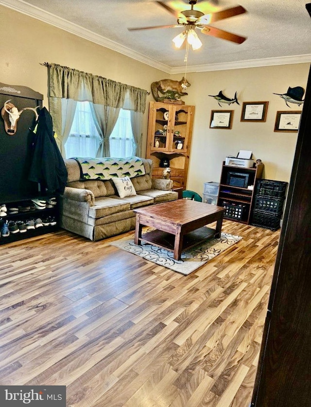 living room featuring hardwood / wood-style flooring, ceiling fan, crown molding, and a textured ceiling