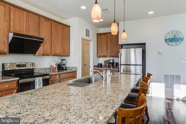 kitchen featuring dark wood-type flooring, a kitchen breakfast bar, sink, range hood, and appliances with stainless steel finishes