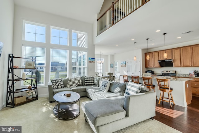 living room featuring a towering ceiling, light hardwood / wood-style floors, and a notable chandelier