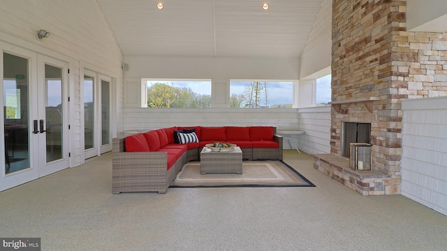 interior space featuring an outdoor stone fireplace, french doors, and vaulted ceiling