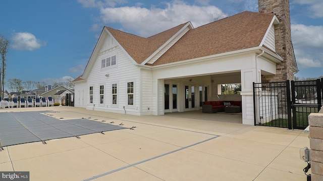 rear view of house with outdoor lounge area, a covered pool, and a patio area