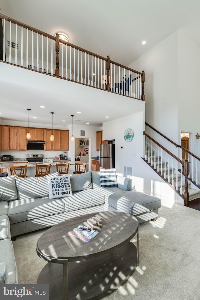 living room featuring a towering ceiling and carpet floors