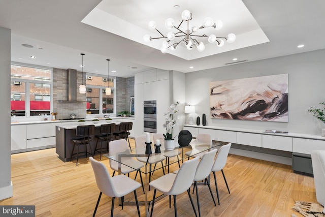 dining room featuring a chandelier, light hardwood / wood-style flooring, and a tray ceiling