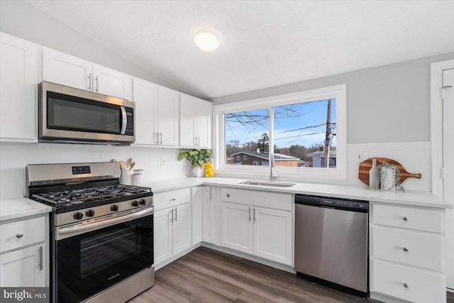 kitchen featuring sink, dark hardwood / wood-style floors, appliances with stainless steel finishes, light stone counters, and white cabinetry