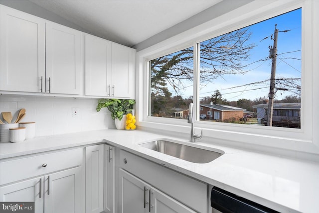 kitchen with backsplash, dishwasher, white cabinetry, and sink