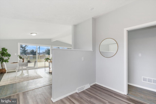 interior space with hardwood / wood-style floors and vaulted ceiling with beams