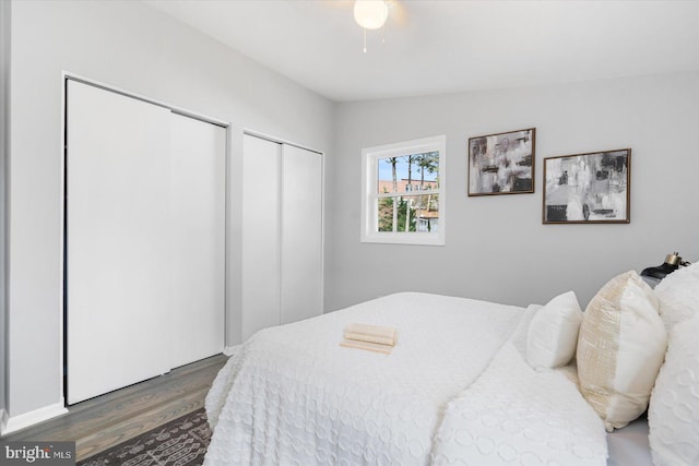 bedroom featuring multiple closets, ceiling fan, dark wood-type flooring, and vaulted ceiling