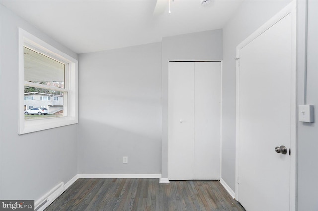 unfurnished bedroom featuring lofted ceiling, a baseboard heating unit, ceiling fan, dark hardwood / wood-style floors, and a closet