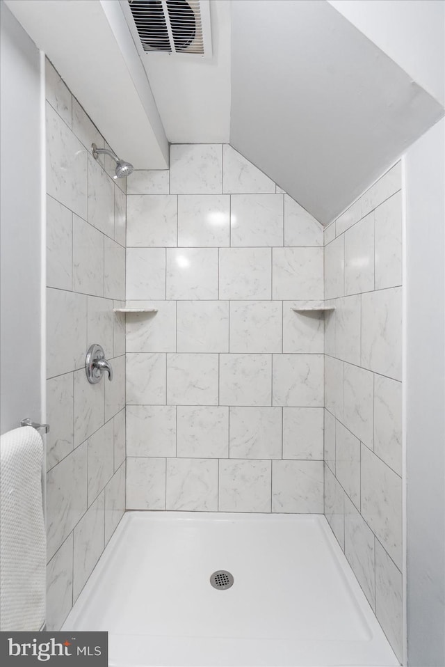 bathroom featuring a tile shower and lofted ceiling