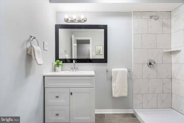 bathroom with tile patterned flooring, a tile shower, and vanity