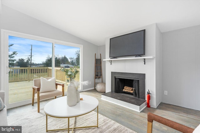 living room featuring a tile fireplace, wood-type flooring, and lofted ceiling