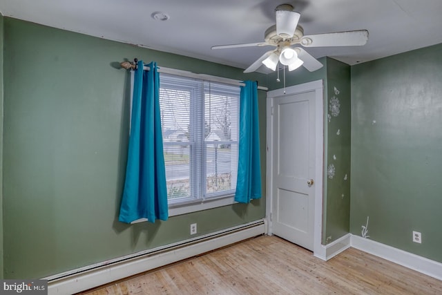 empty room with ceiling fan, light wood-type flooring, and baseboard heating