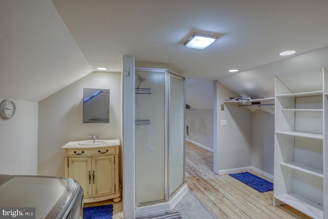 bathroom with an enclosed shower, vanity, vaulted ceiling, hardwood / wood-style floors, and washer / dryer