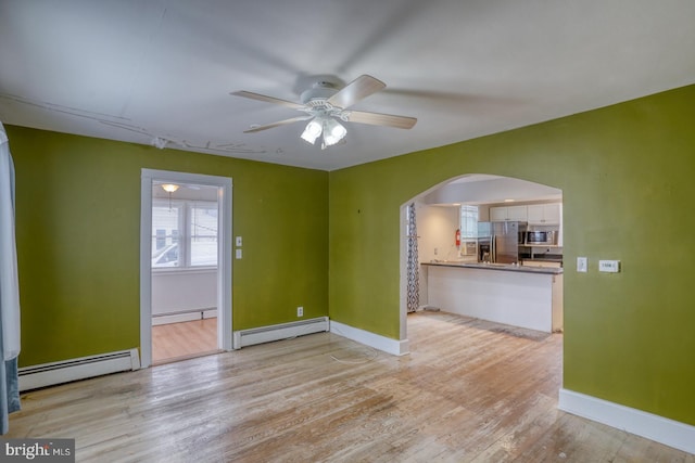 interior space with light hardwood / wood-style flooring, ceiling fan, and a baseboard heating unit