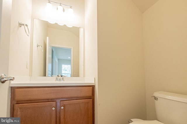 bathroom with vanity, lofted ceiling, and toilet