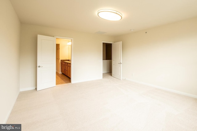 unfurnished bedroom with connected bathroom and light carpet