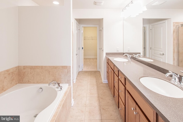 bathroom featuring vanity, a relaxing tiled tub, and tile patterned floors