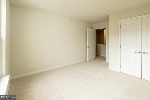 unfurnished bedroom with light carpet and a closet