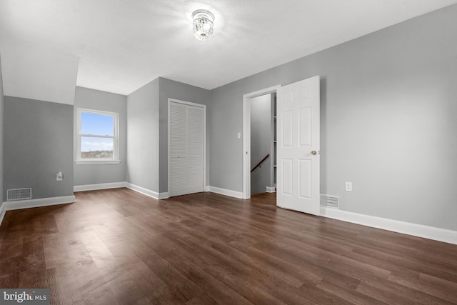 unfurnished bedroom featuring a closet and dark wood-type flooring