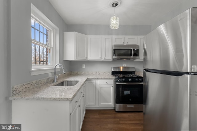 kitchen with light stone counters, stainless steel appliances, sink, decorative light fixtures, and white cabinets