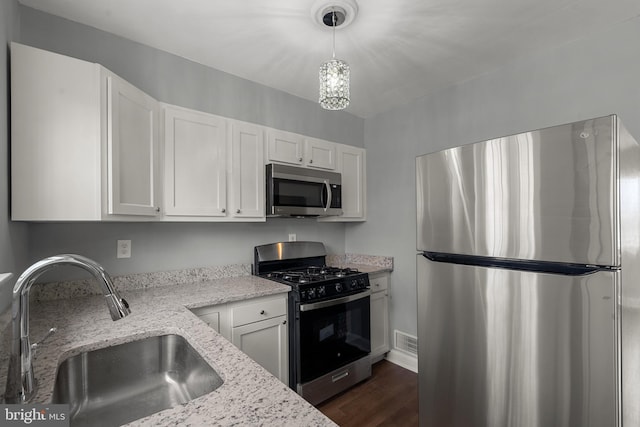 kitchen with light stone countertops, stainless steel appliances, white cabinets, and sink