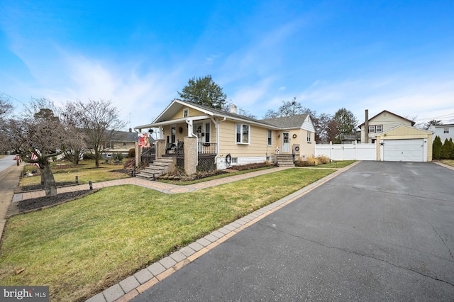 view of front of house featuring an outbuilding, a porch, a garage, and a front lawn